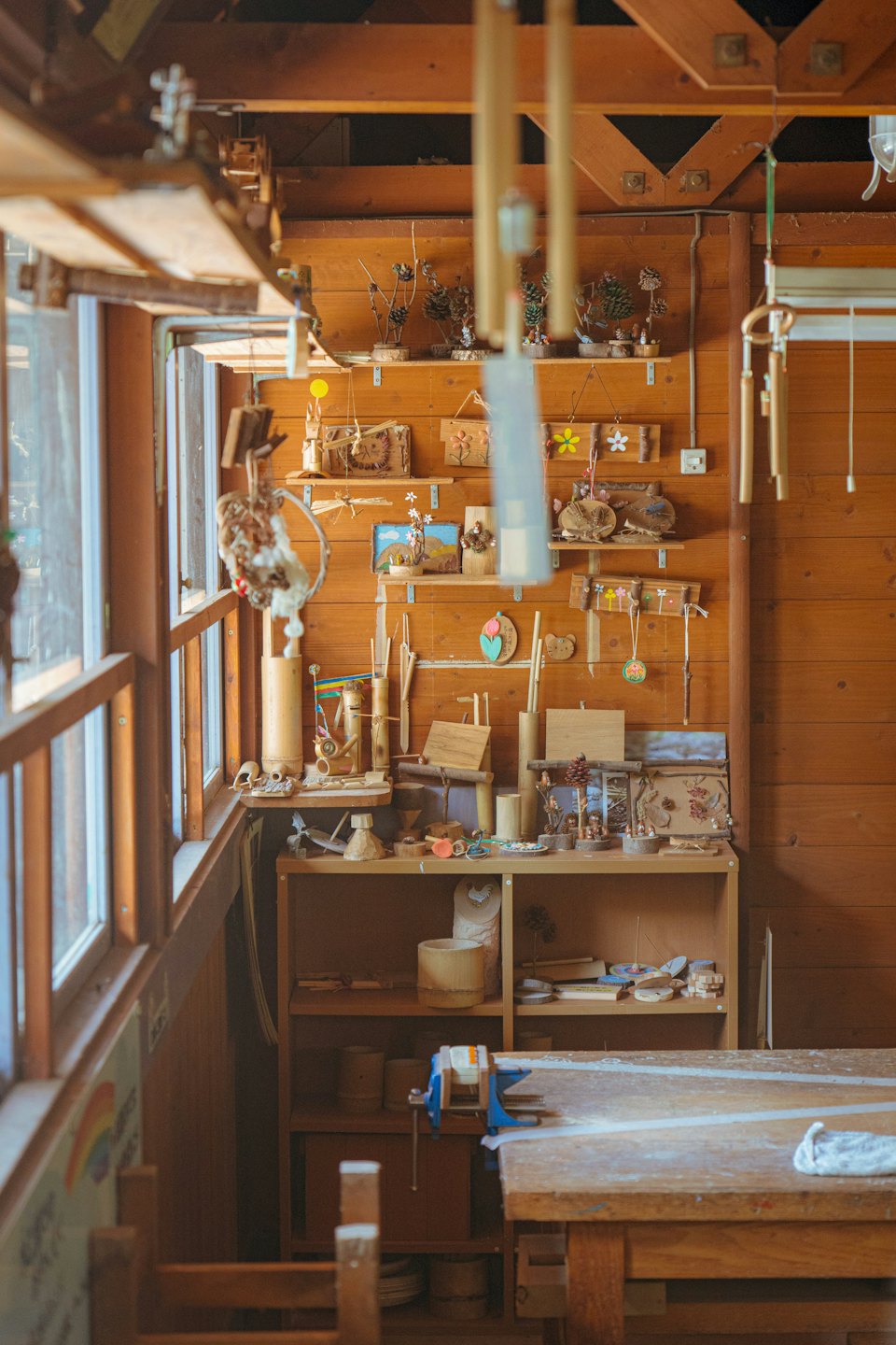 Holzwerkbank mit Werkzeugen und handgefertigtem Kunsthandwerk an der Wand.
