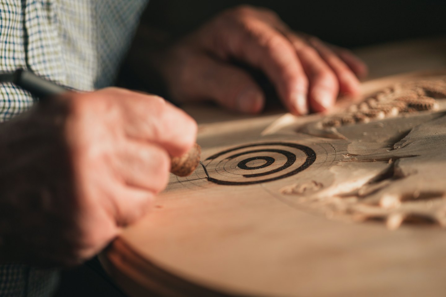 Hände schnitzen kunstvolles Spiraldesign in helles Holz.