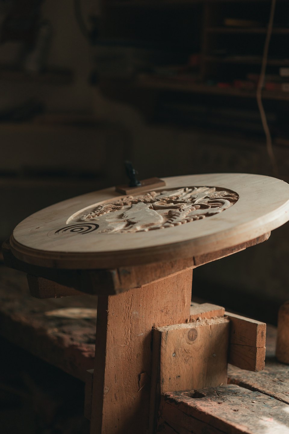 Holzkunstwerk auf einem rustikalen Ständer in einer Werkstatt.